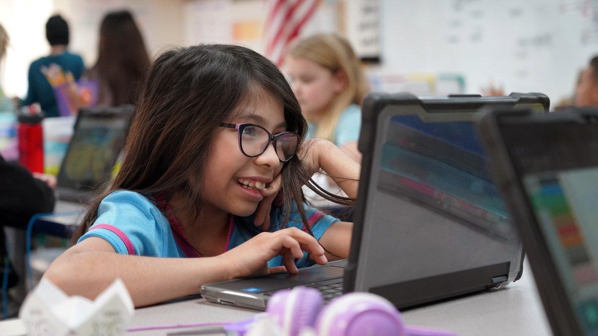 girl with glasses smiling while working on laptop